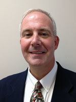 a man wearing a suit and tie smiling at the camera