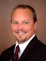 a man wearing a suit and tie smiling at the camera