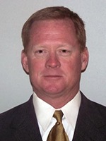 a man wearing a suit and tie smiling at the camera