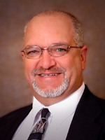 a man wearing a suit and tie smiling at the camera