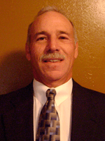 a man wearing a suit and tie smiling at the camera